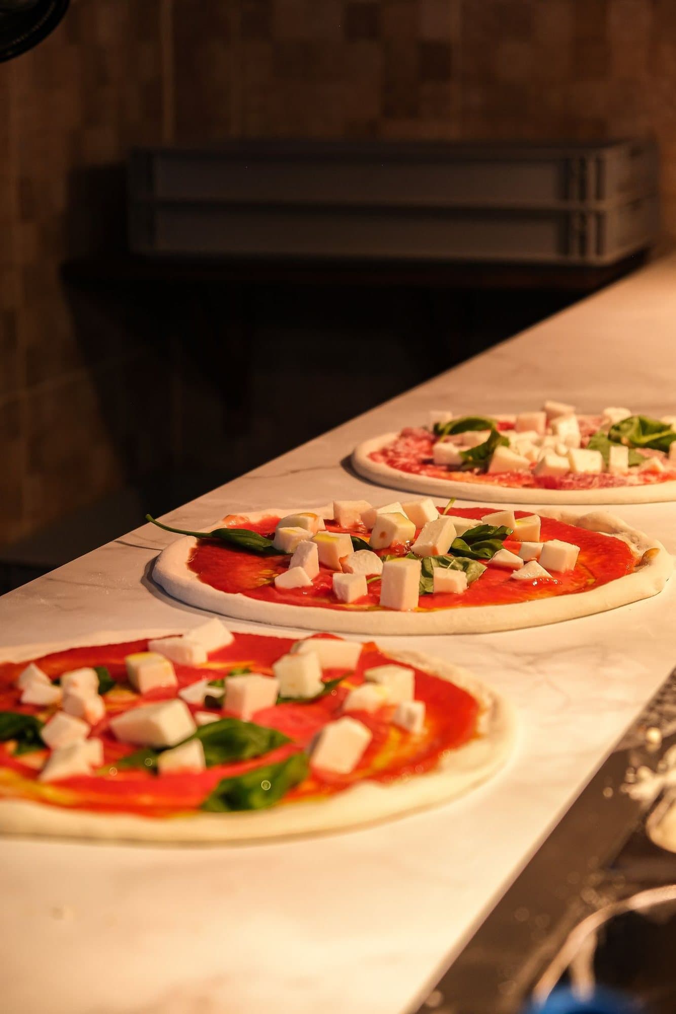 Pizzas lined up on the marble pass